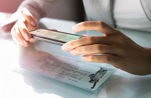 man taking picture of check with smartphone